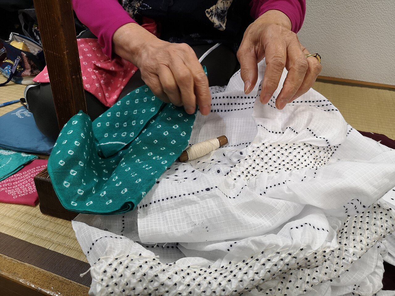 糸でくくった有松の鹿の子絞の白い布と、染め上がった布