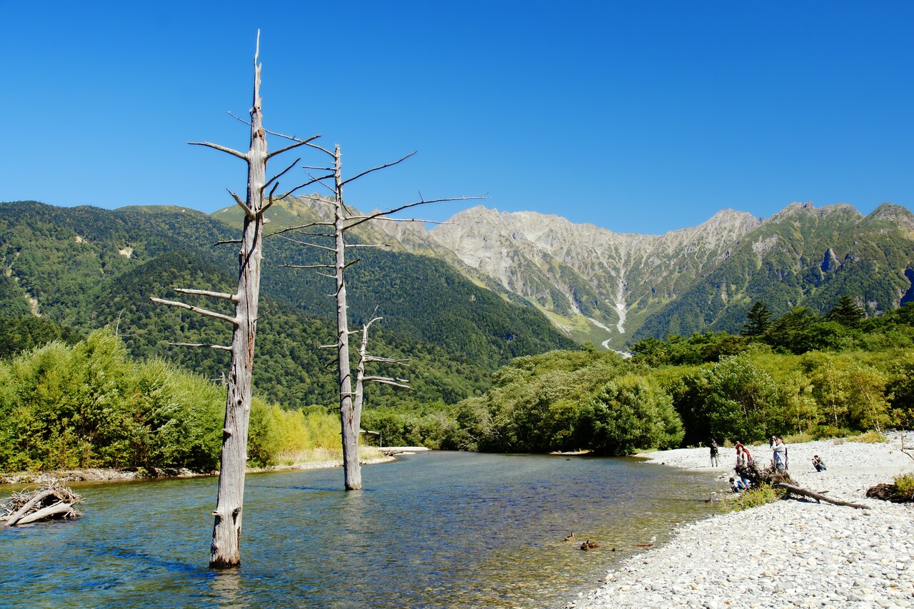 穂高連峰を背景に、水辺に立ち枯れの木が立つ上高地・大正池