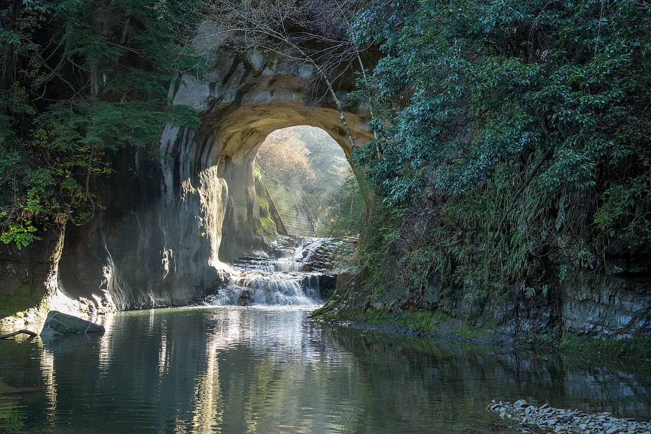 森に囲まれた亀岩の洞窟から光が差し込み、川が手前へ流れる