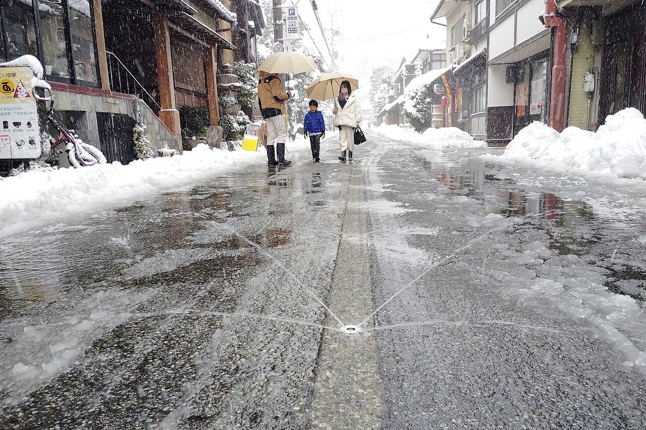 積雪の残る城崎温泉の道路で水を出す消雪設備